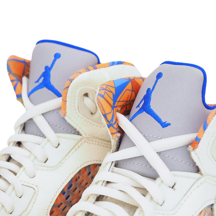 Close-up of a pair of Jordan 5 sneakers with a prominent blue jumpman logo and 3M reflective tongue on a white background