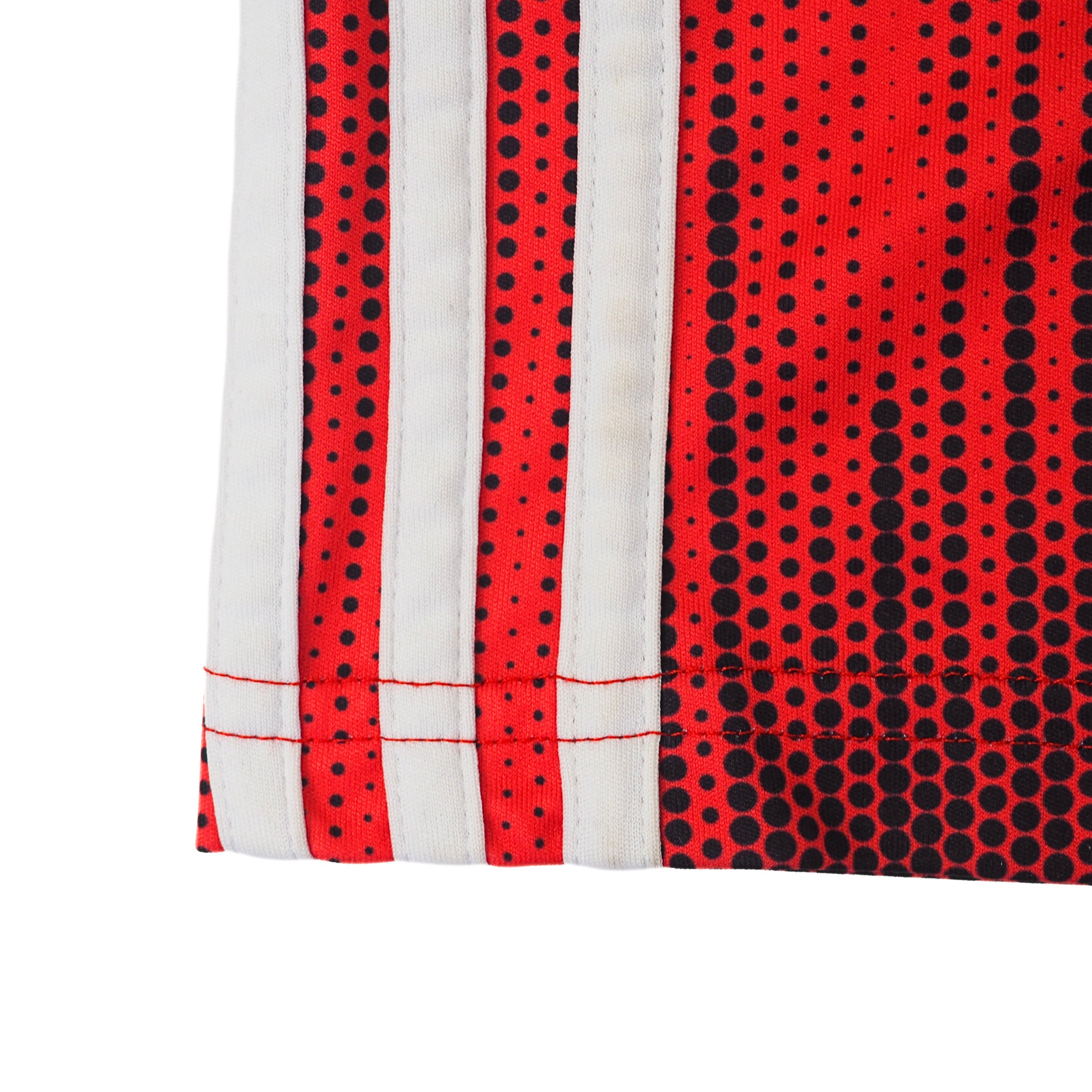 Close up of white adidas three strips on the side of a red and black soccer jersey