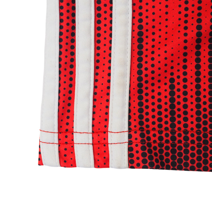 Close up of white adidas three strips on the side of a red and black soccer jersey