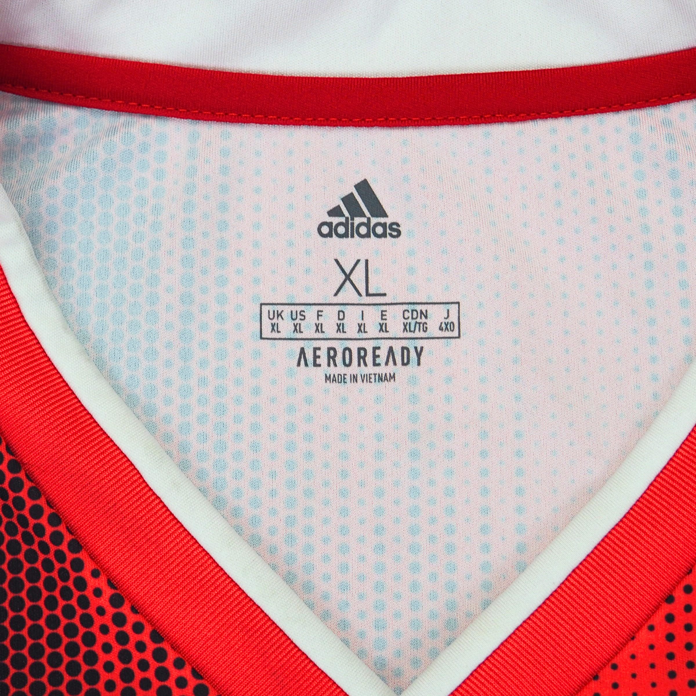 Close up of the inside collar and size information of a red and black adidas soccer jersey on a white background