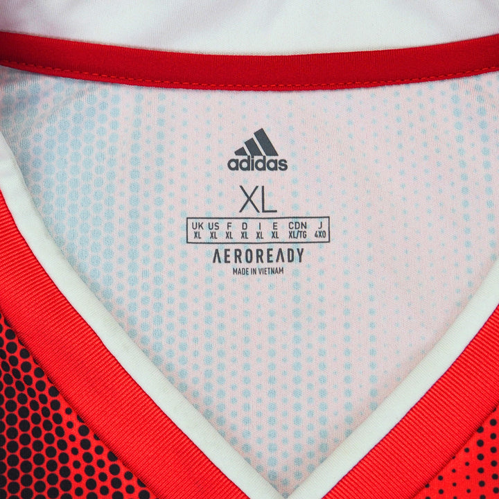 Close up of the inside collar and size information of a red and black adidas soccer jersey on a white background