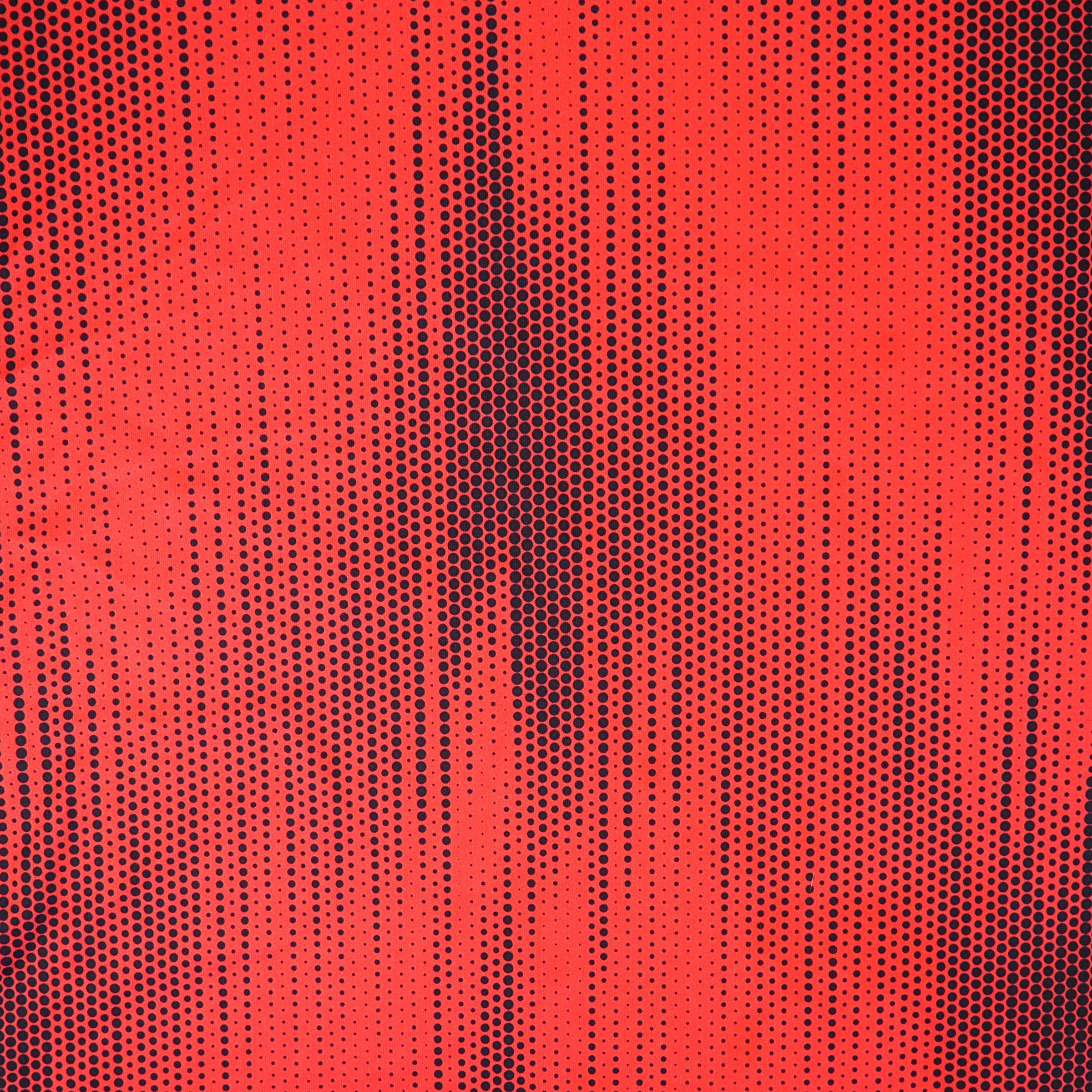 Close up of a red soccer jersey with a black polkadot pattern
