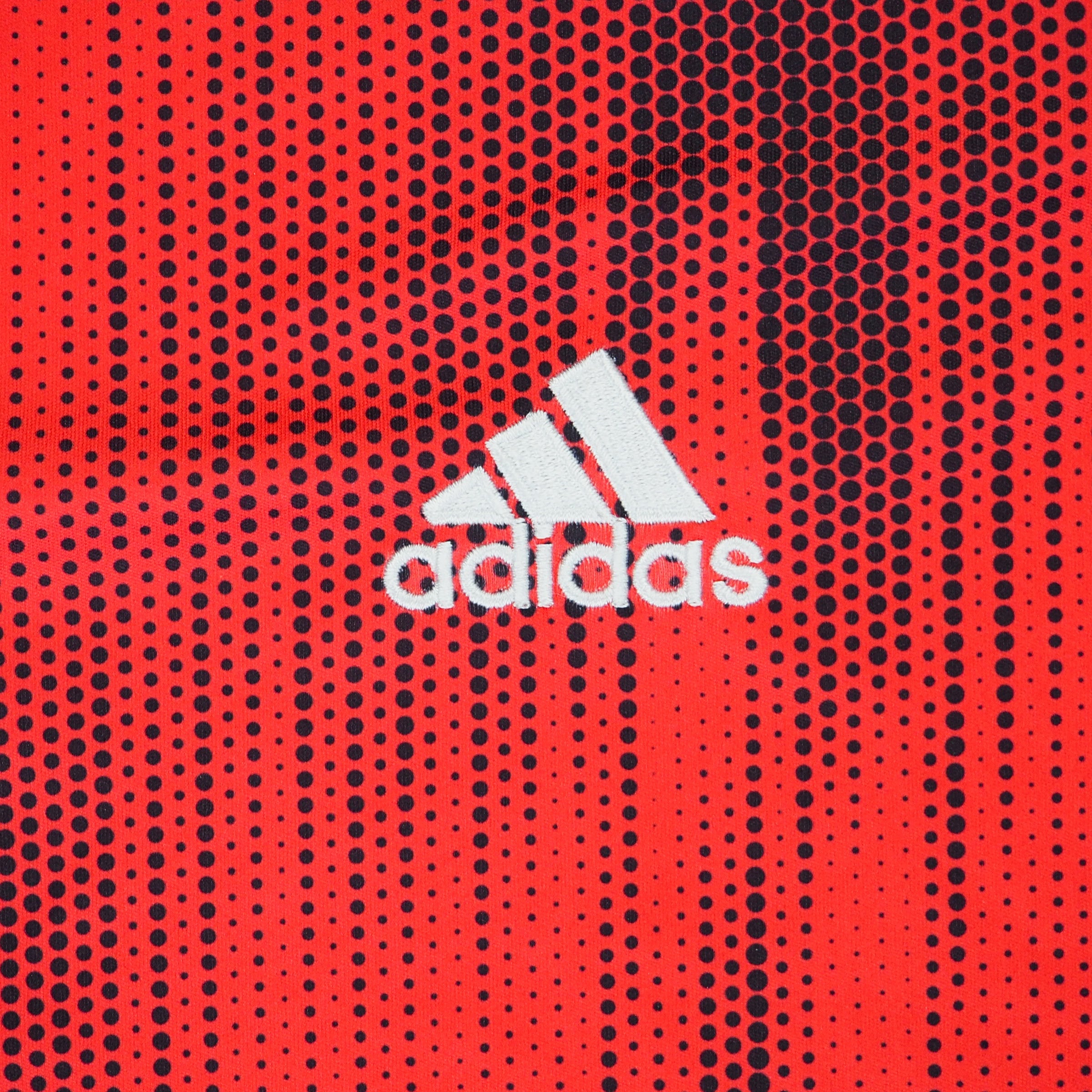 Close up of a red soccer jersey with black polkadots and a white adidas logo