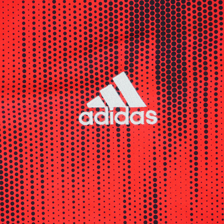 Close up of a red soccer jersey with black polkadots and a white adidas logo