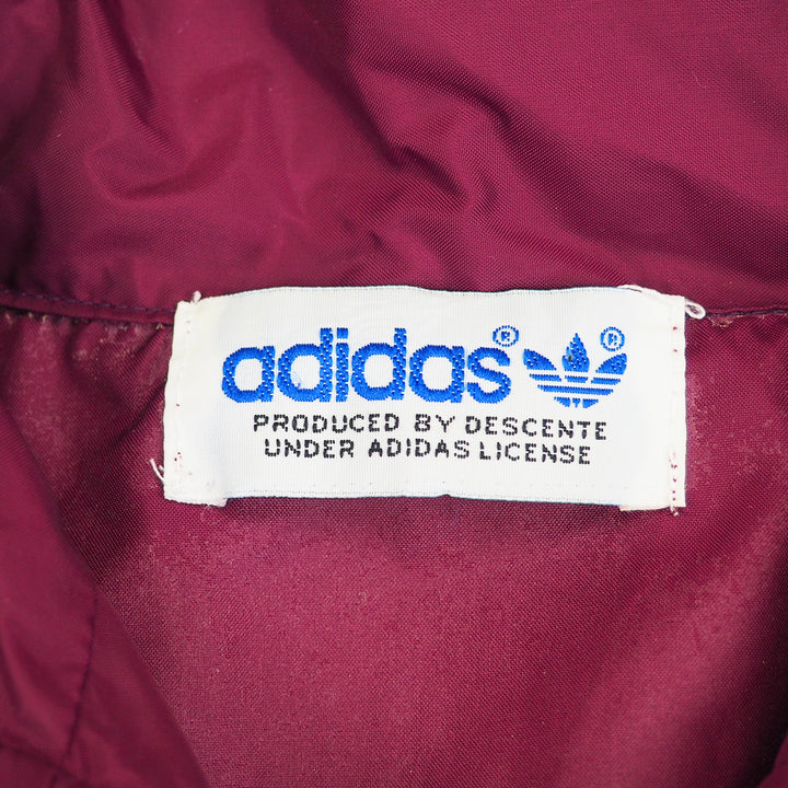 Close-up of an Adidas by Descente label on a maroon fabric background