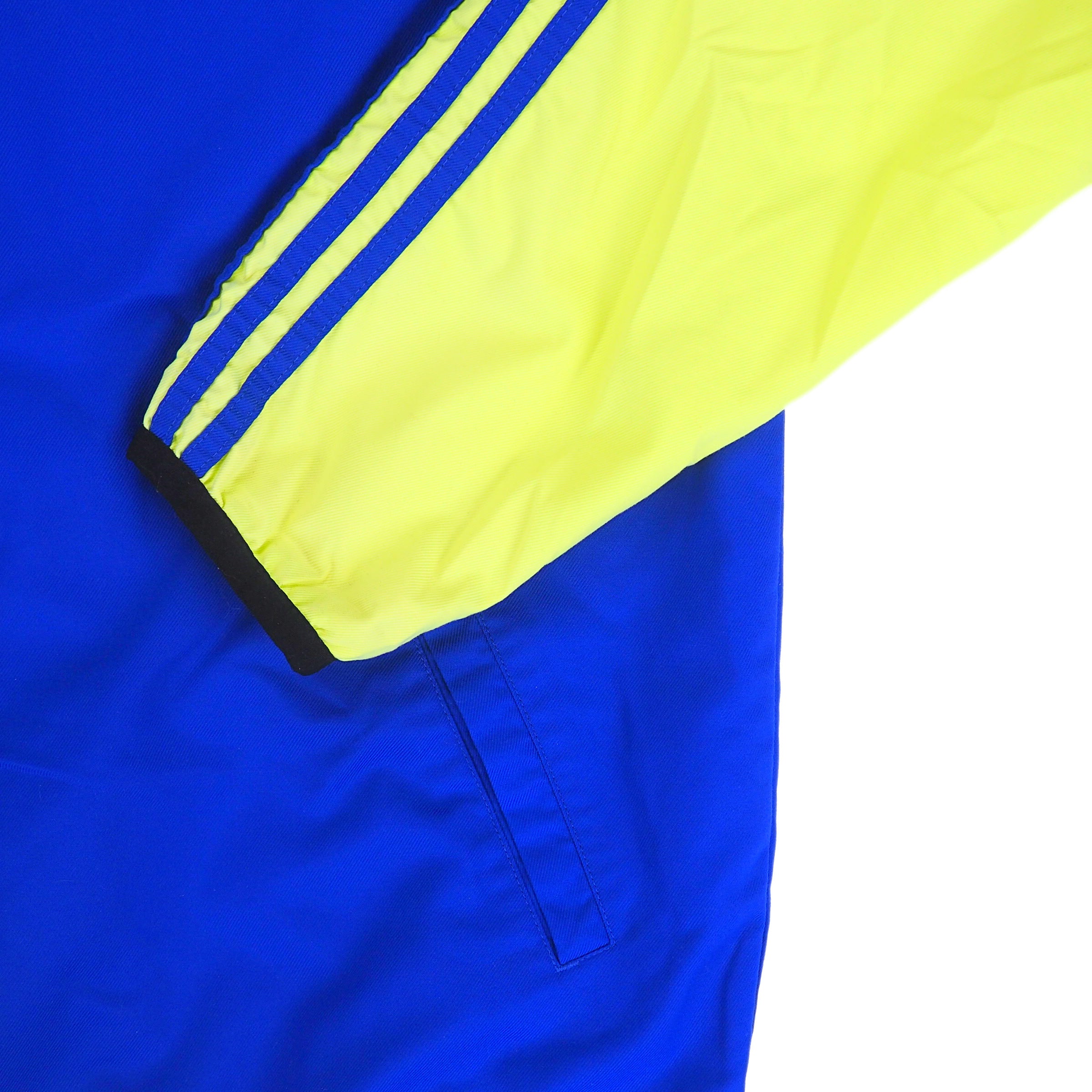 Close up of a neon yellow sleeve with stripes folded over the blue body of a jacket