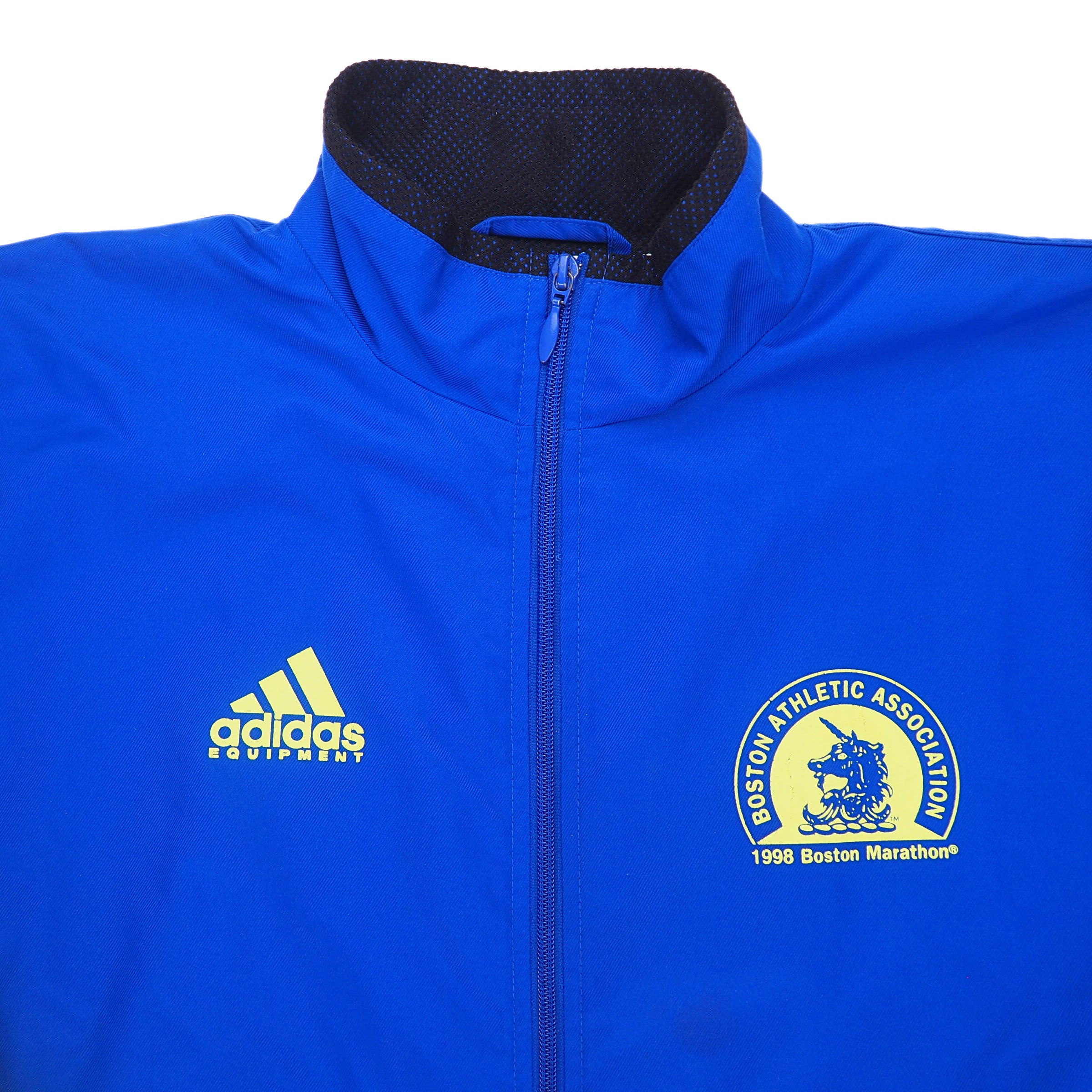 Detail of the chest and collar of a blue jacket with adidas equipment and BAA logos