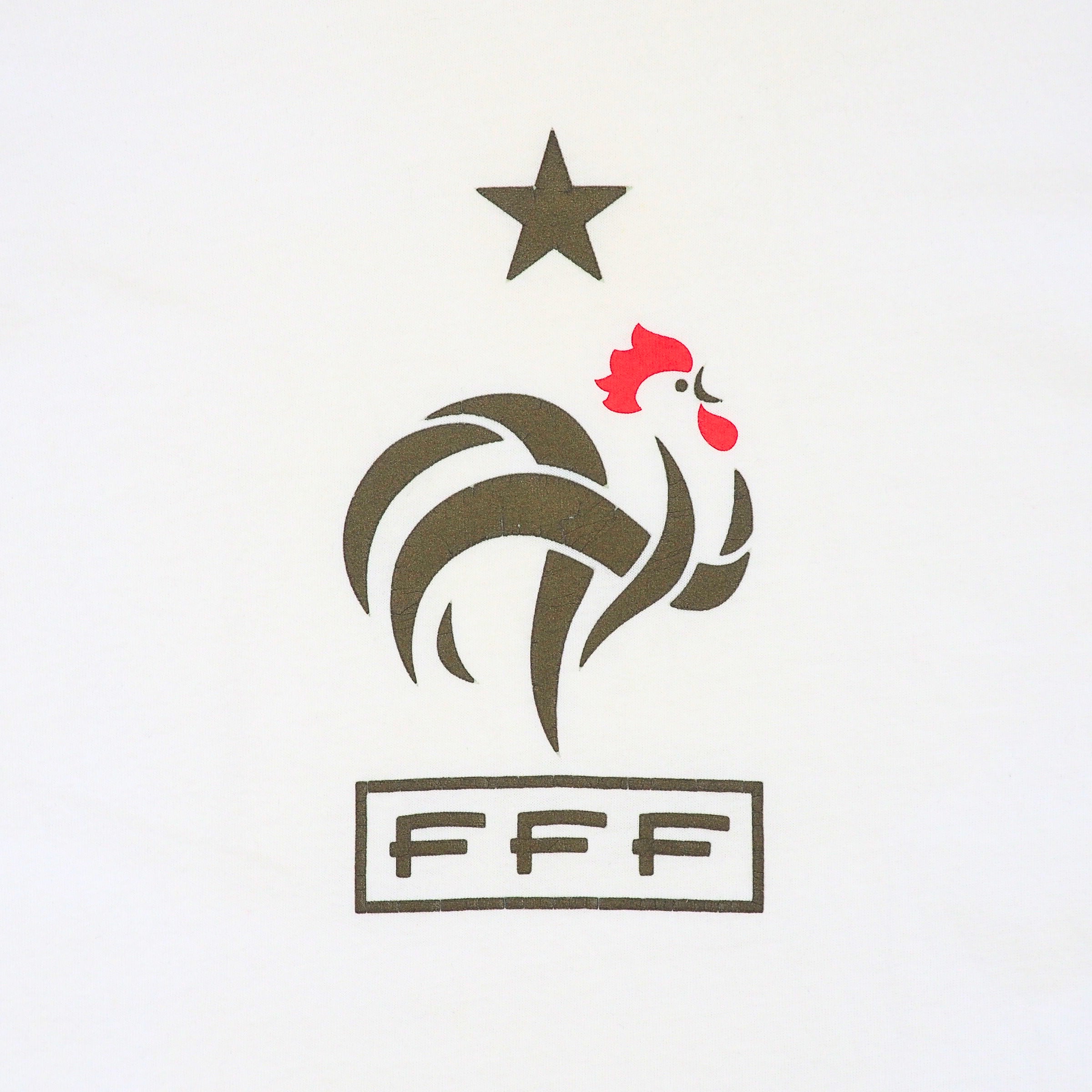 Close up detail of a white t-shirt with a graphic of a star, a cockerel and letters FFF