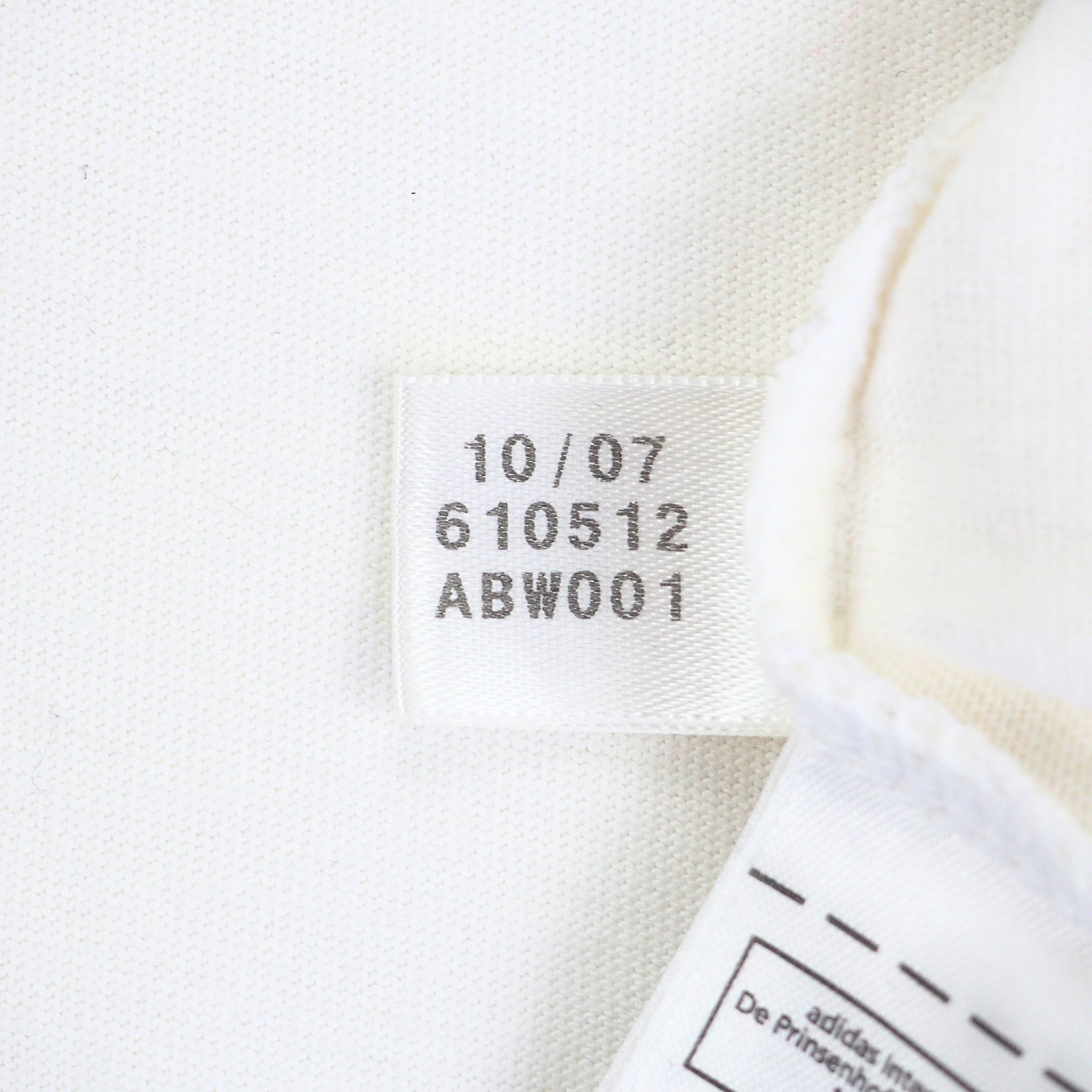 Close up of an adidas manufacturing tag on the inside of a white t-shirt