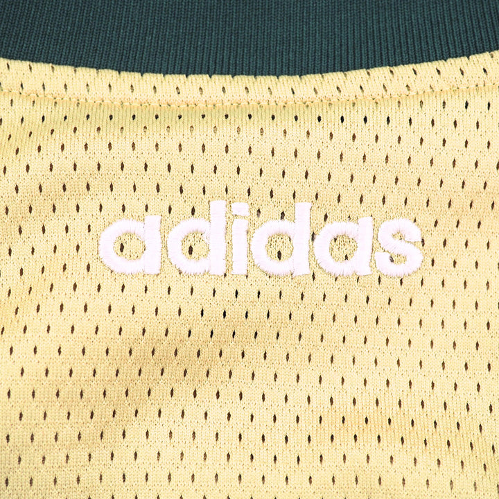 Close-up of Adidas logo on a gold mesh fabric background