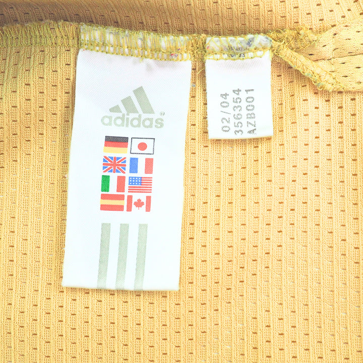 Close-up of Adidas International flag label on a textured gold fabric background