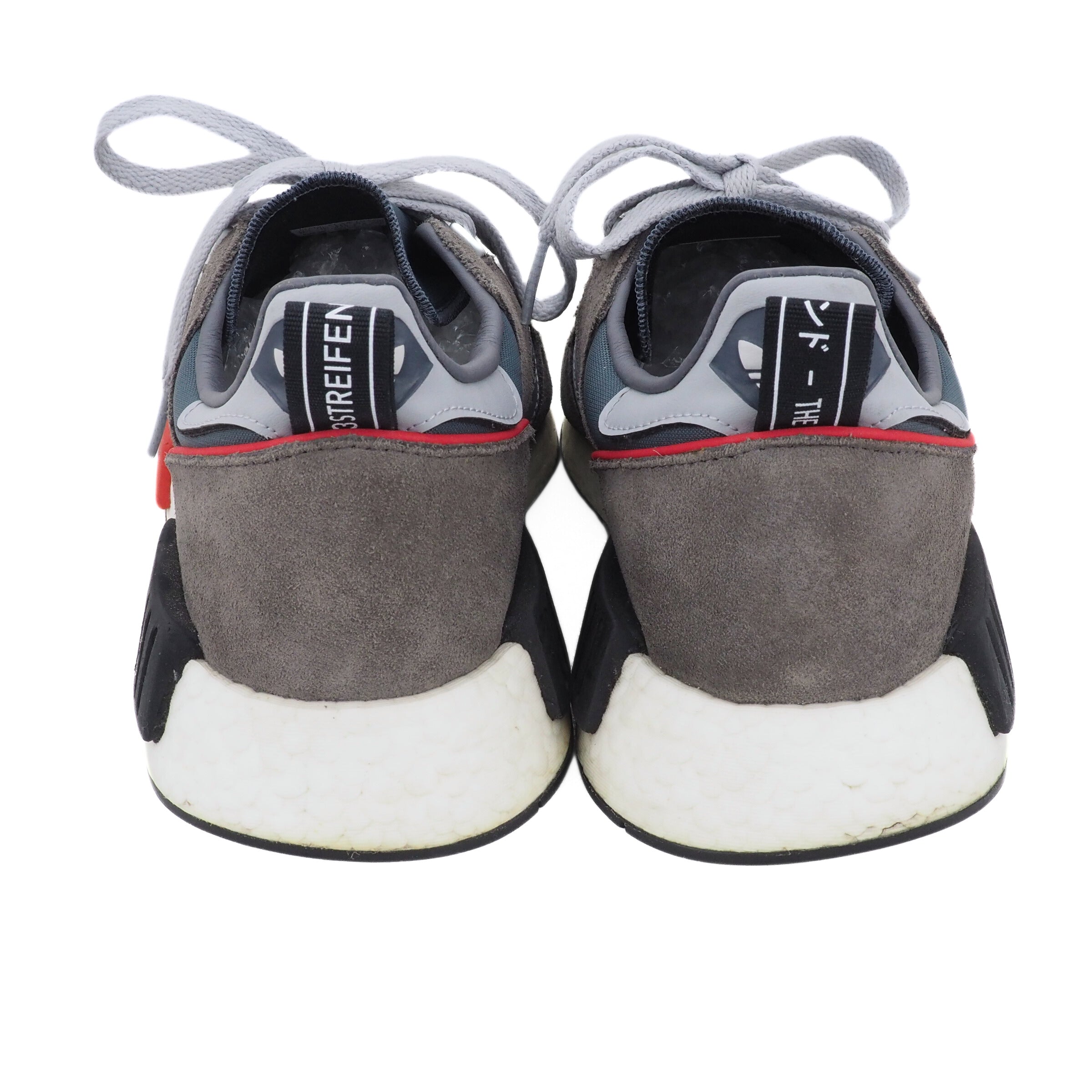 Back view of a pair of gray and black sneakers with white soles on a white background