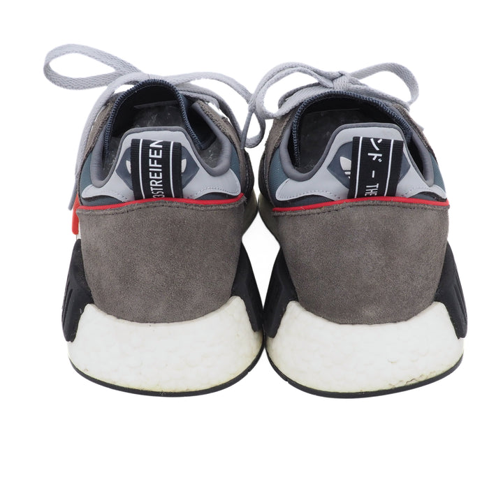 Back view of a pair of gray and black sneakers with white soles on a white background