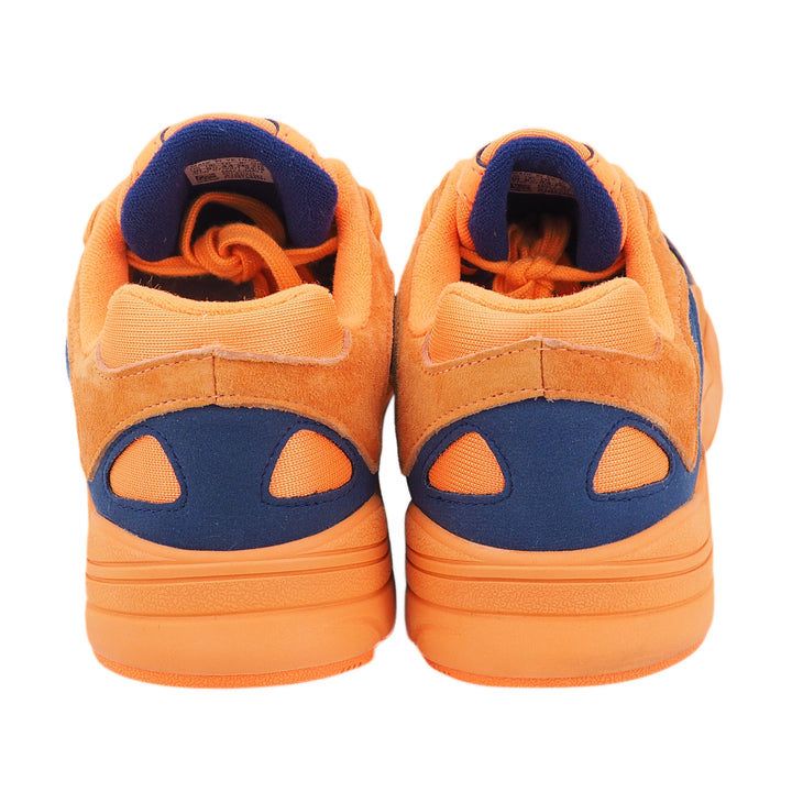 Back view of the heel of a pair of orange and blue sneakers on a white background