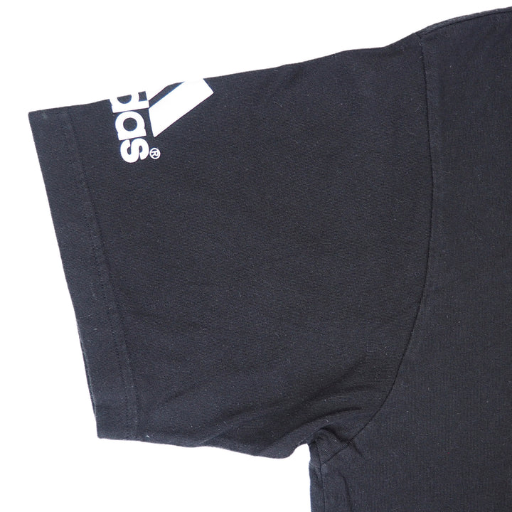 Detail of the sleeve of a black adidas t-shirt on a white background
