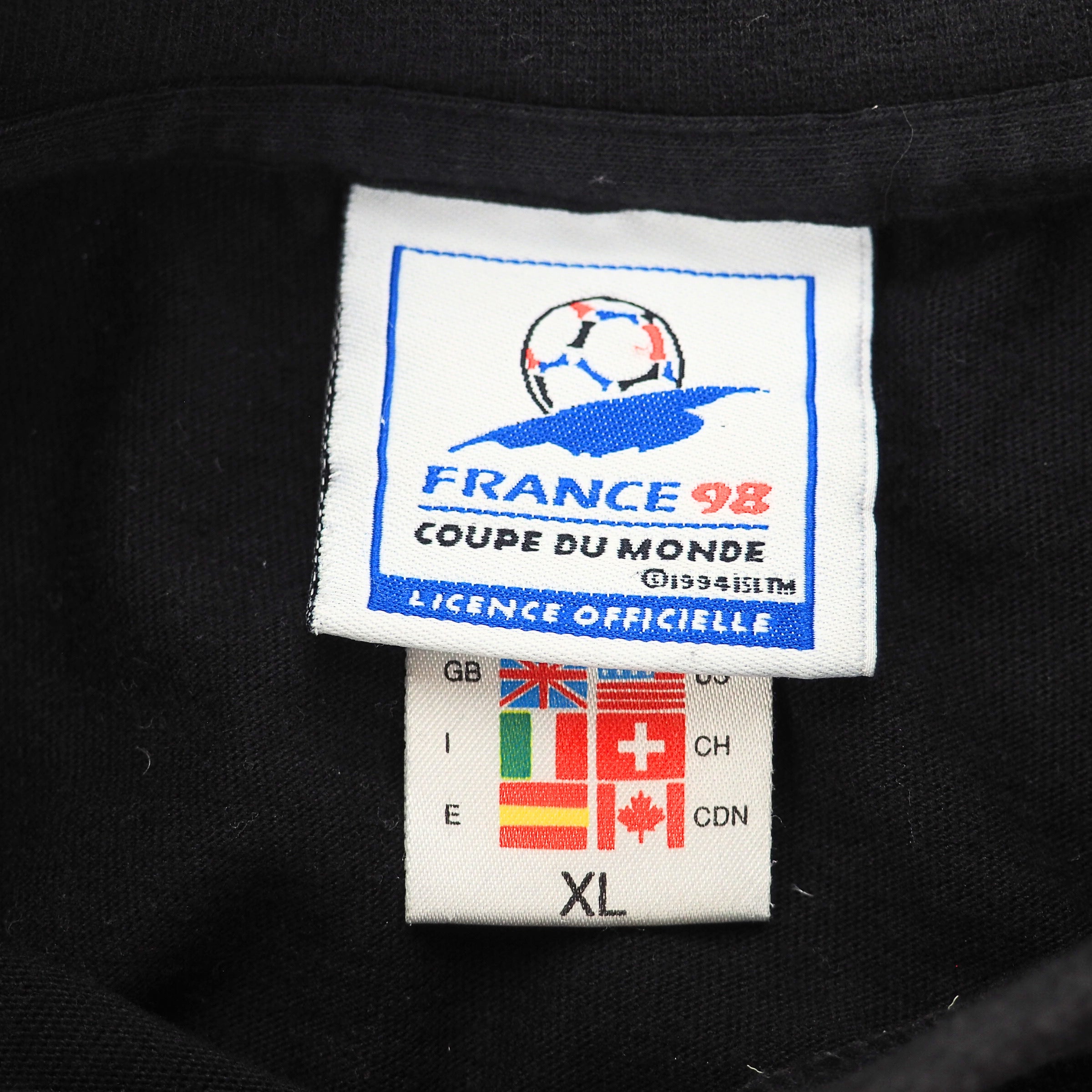 Close up of a France 98 and adidas flag tag label on the inside collar of a black t-shirt