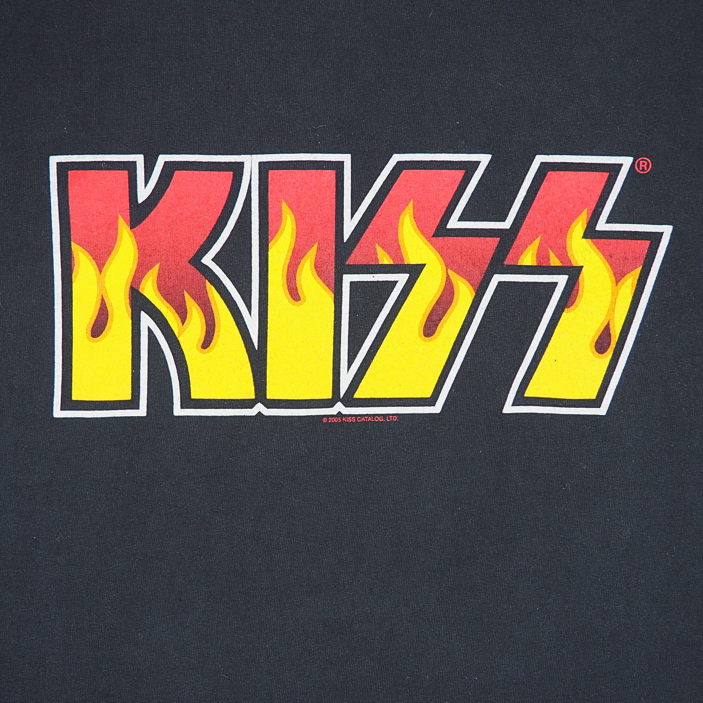 Close-up of a black T-shirt featuring the KISS band logo in bold letters with red and yellow flames integrated into the design.