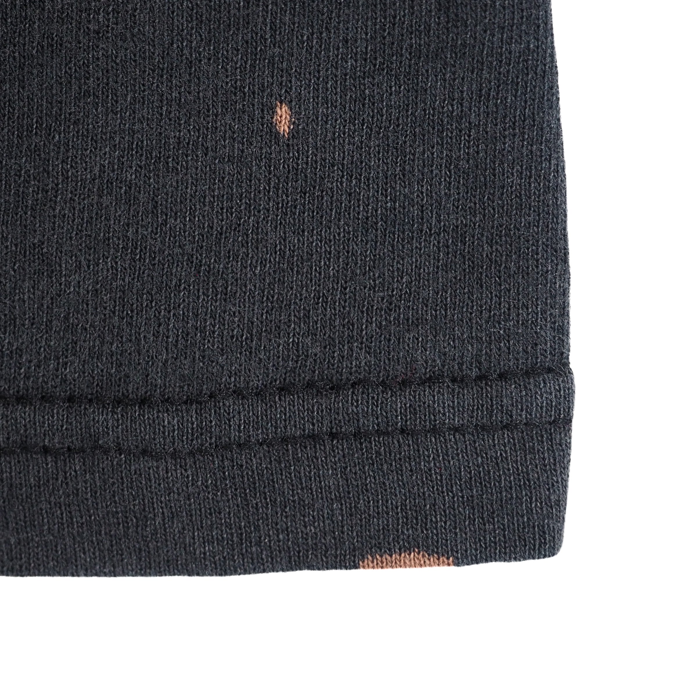 Close up of the hem of a black t-shirt with two small bleached spots