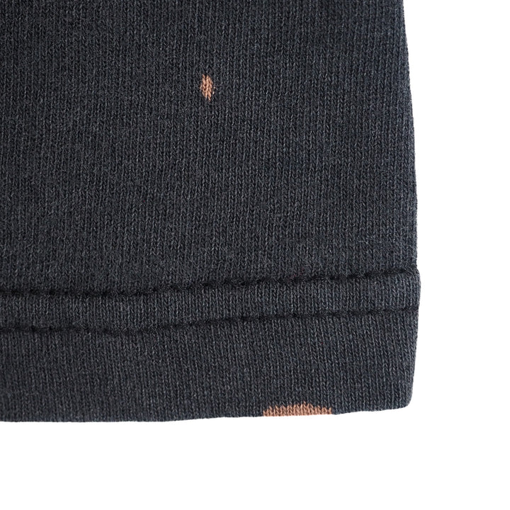 Close up of the hem of a black t-shirt with two small bleached spots