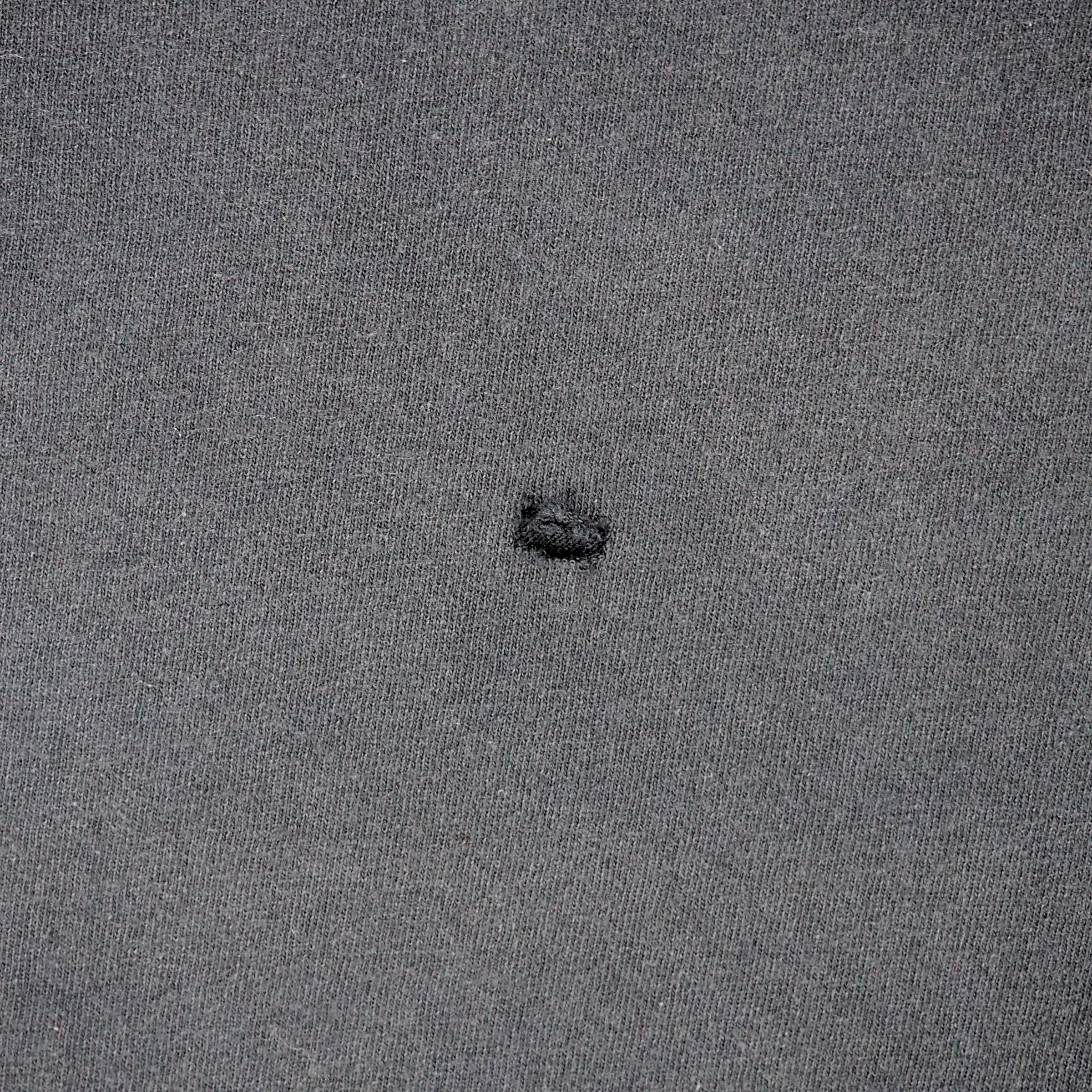 Detail of a hole in a piece of black cotton fabric