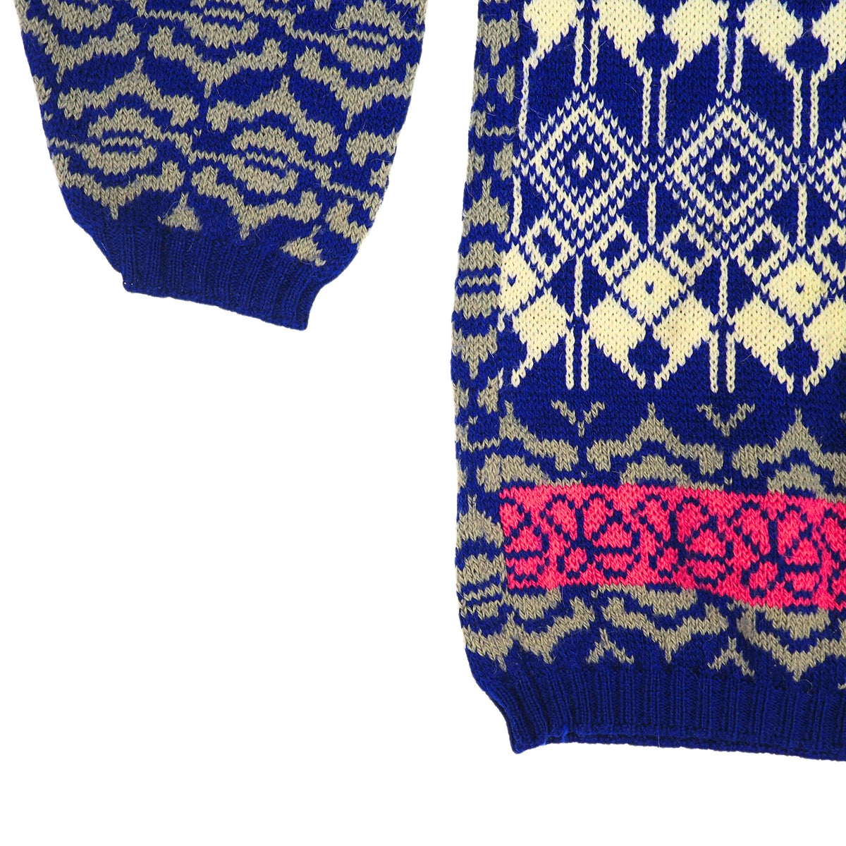 Detail of the sleeve and hem of a colourful knitted sweater in blue, cream, pink and grey.