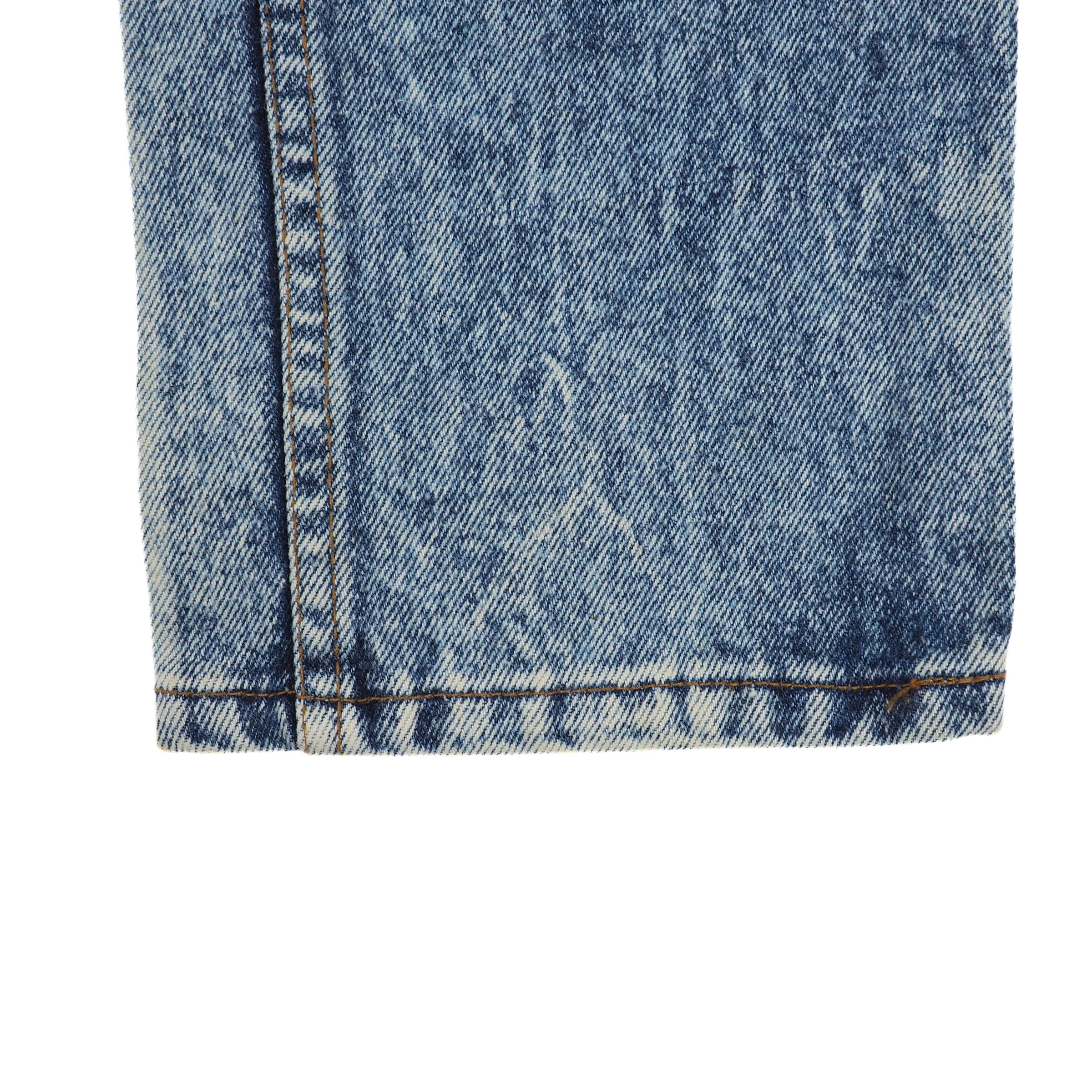 Close-up of blue denim jean pant leg cuff with a white background