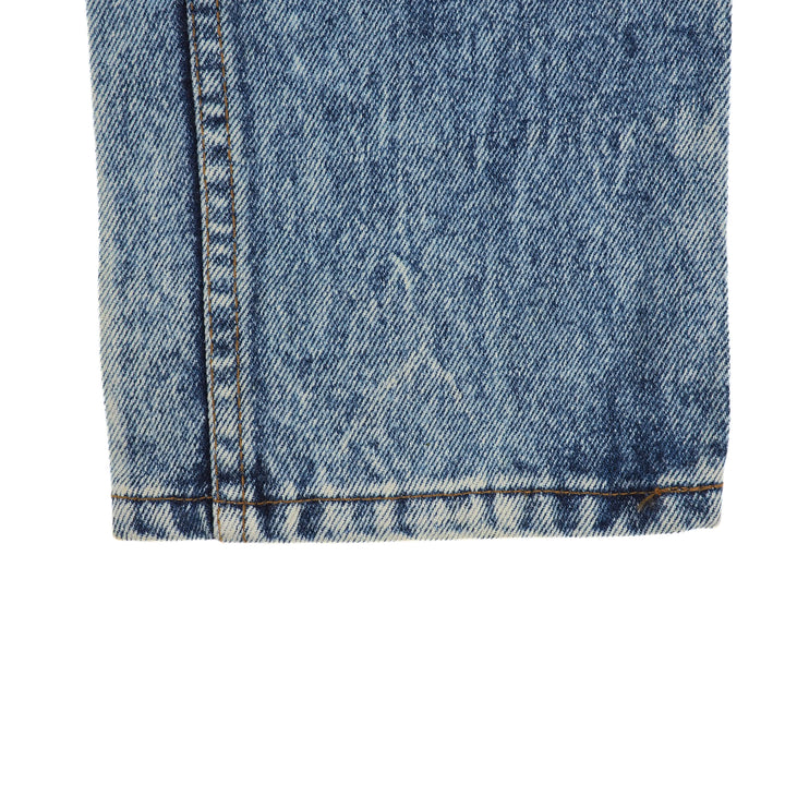 Close-up of blue denim jean pant leg cuff with a white background