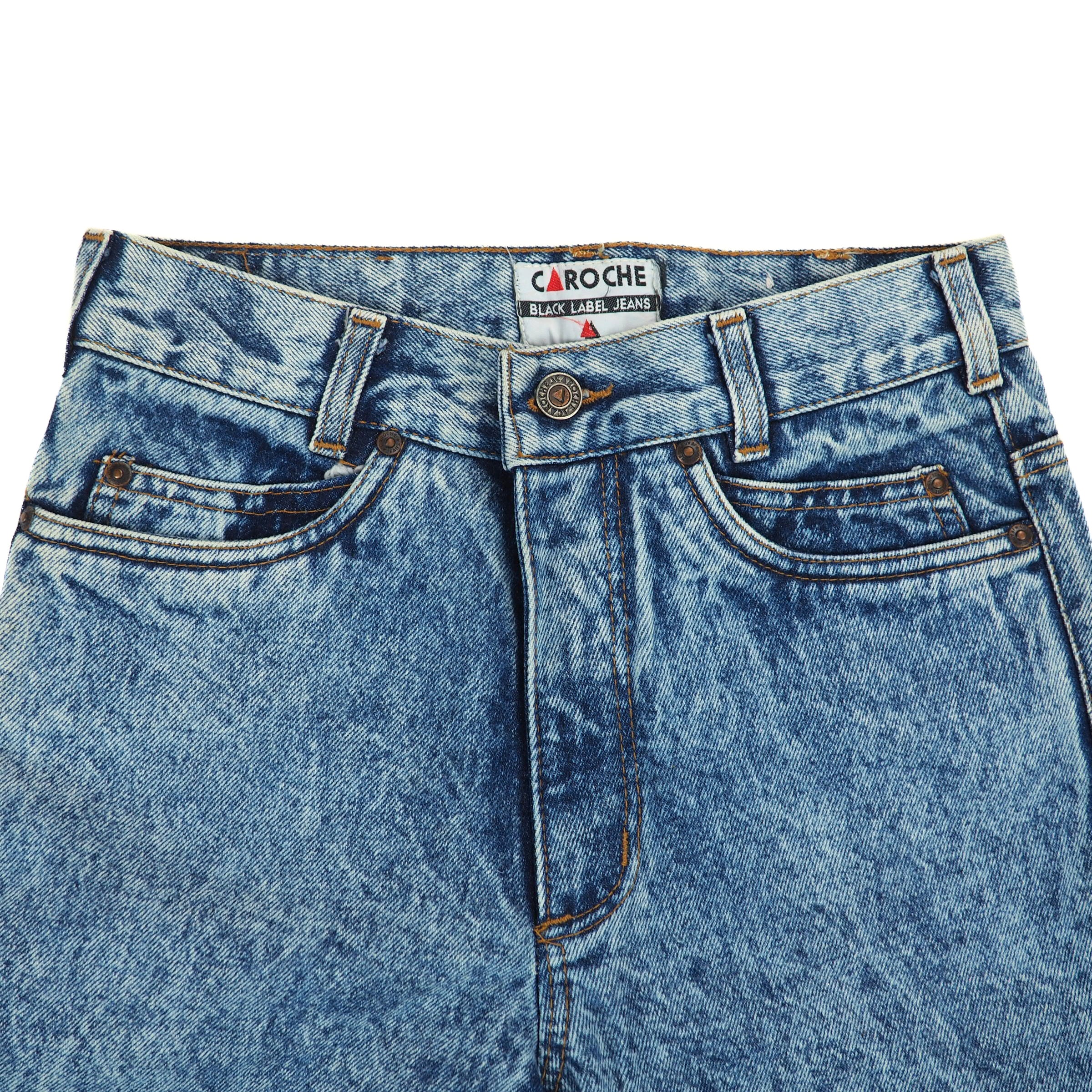 Close up of the waist area of a pair of blue jeans with Caroche label on a white background