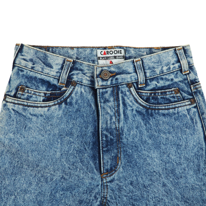 Close up of the waist area of a pair of blue jeans with Caroche label on a white background