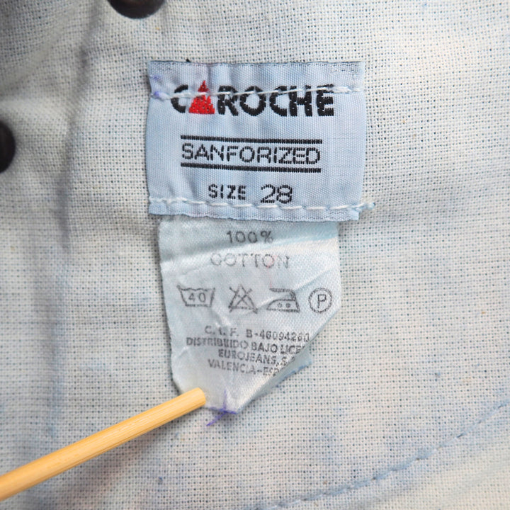 Clothing care label on a white cotton fabric surface with 'Caroche' branding.