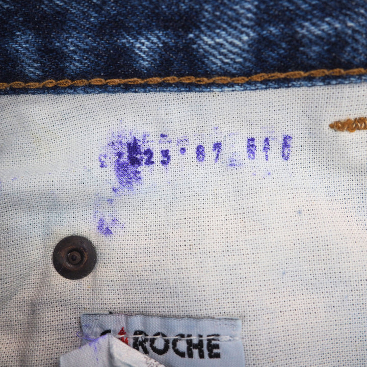Close-up of a denim fabric and interior lining with a rivet and care label, featuring the brand 'Caroche'.