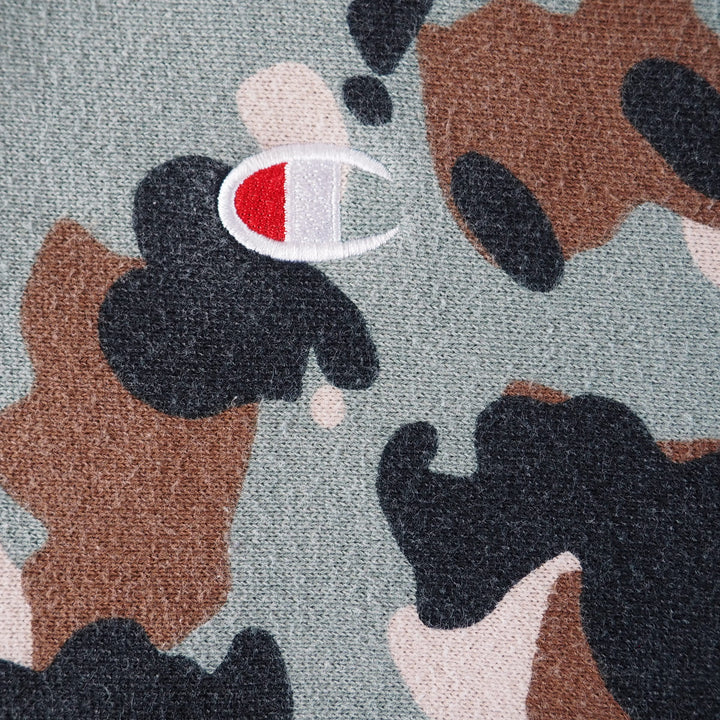 Close-up of a camouflage pattern with a Champion 'C' brand logo on a textured fabric background