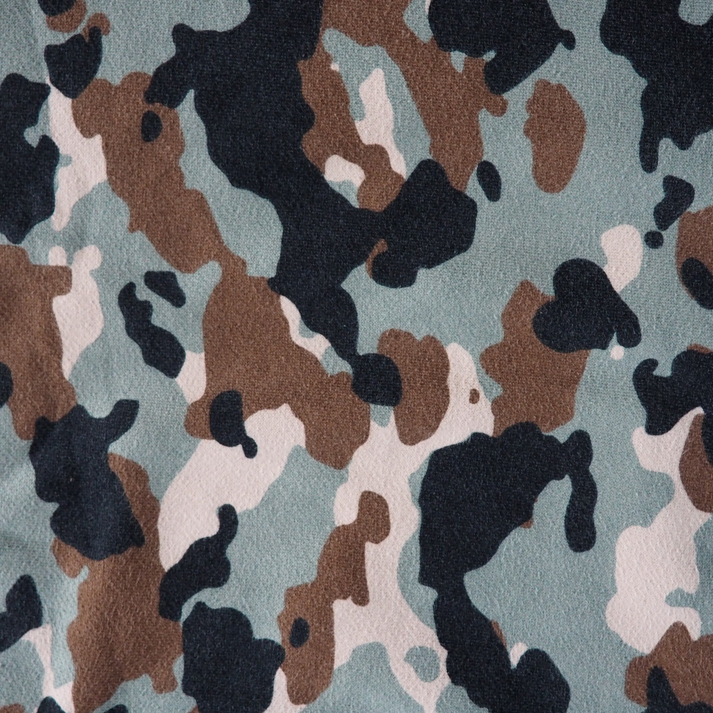 Camouflage pattern with black, brown, and beige on a green background