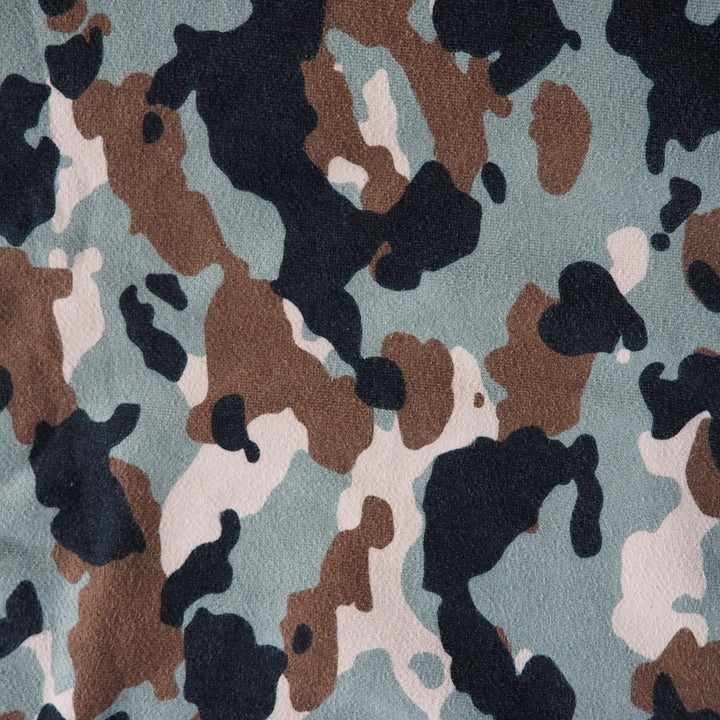 Camouflage pattern with black, brown, and beige on a green background