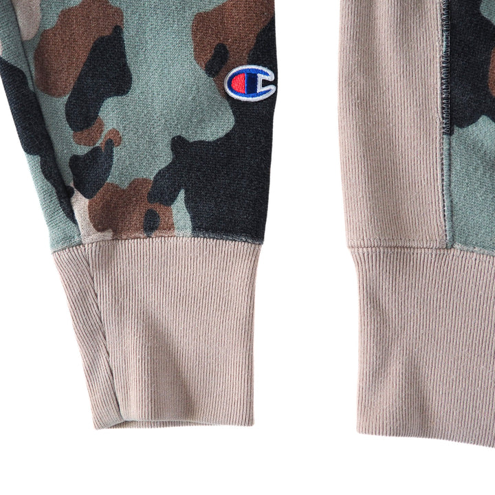 Sleeve and body detail of a camouflage-patterned sweatshirt with Champion logo on a white background