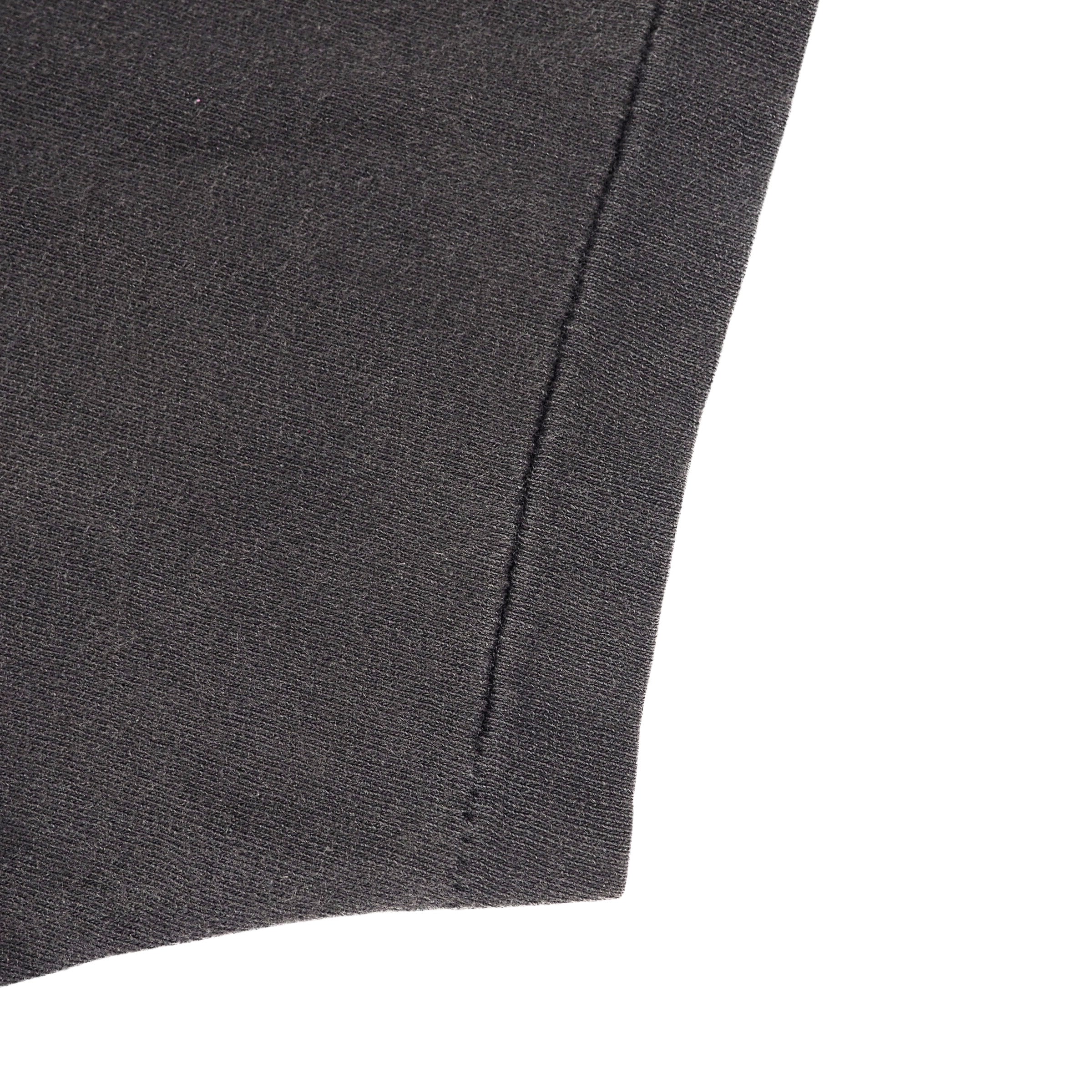Close-up detail of a dark charcoal gray knit fabric, showing a clean stitched seam against a solid white background.