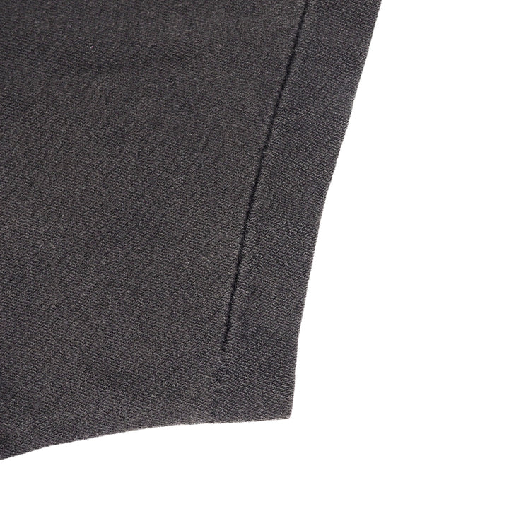 Close-up detail of a dark charcoal gray knit fabric, showing a clean stitched seam against a solid white background.