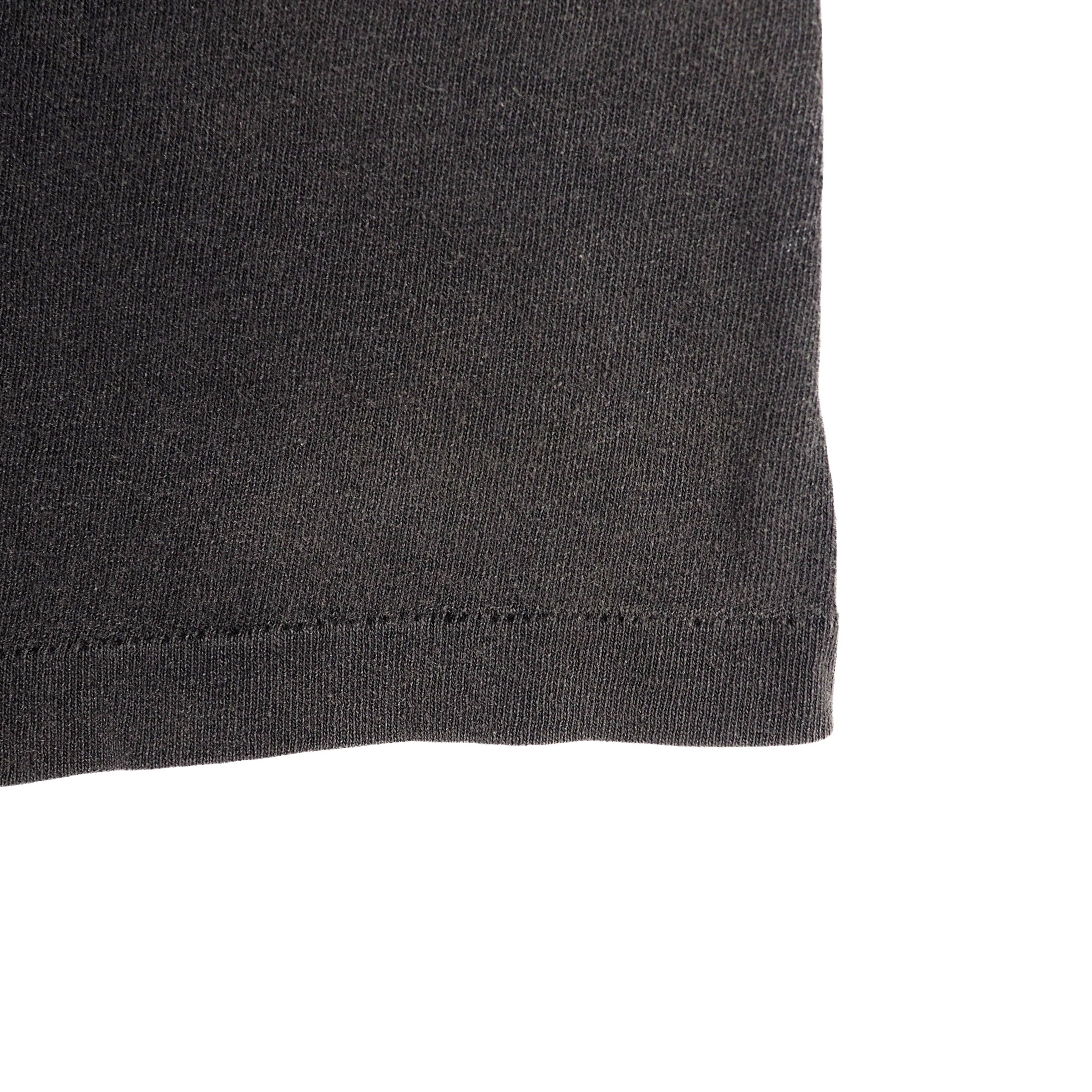 Close up of the hem of a faded black single stitch vintage t-shirt on a white background
