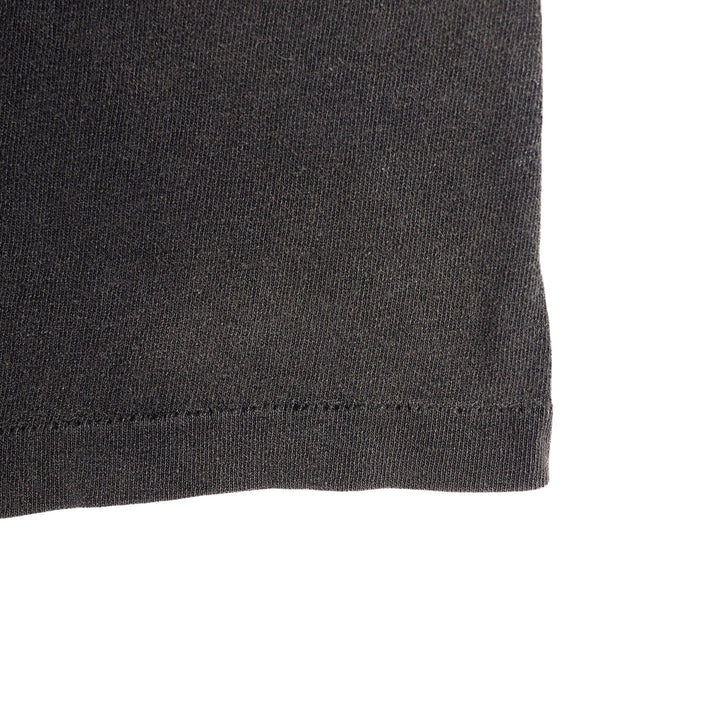 Close up of the hem of a faded black single stitch vintage t-shirt on a white background