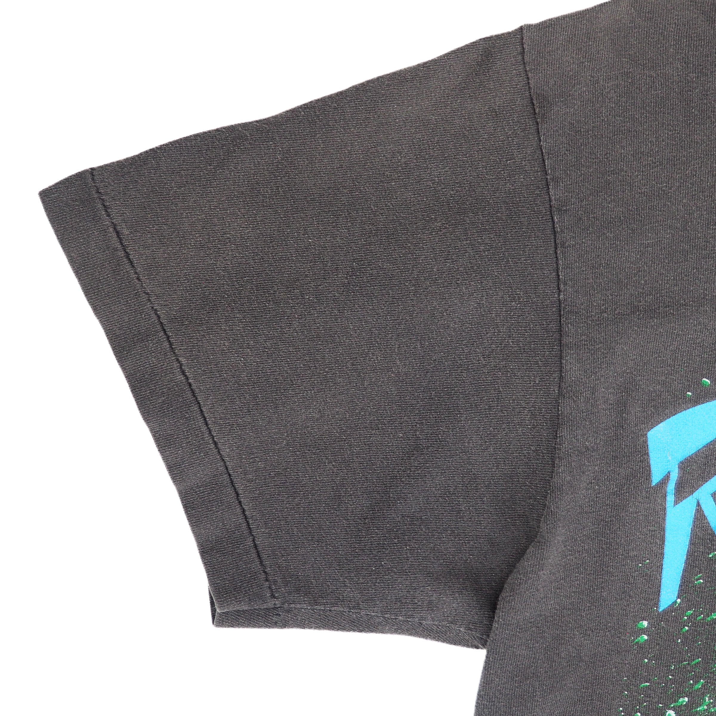 Close up of the sleeve of a faded black single stitch vintage t-shirt on a white background