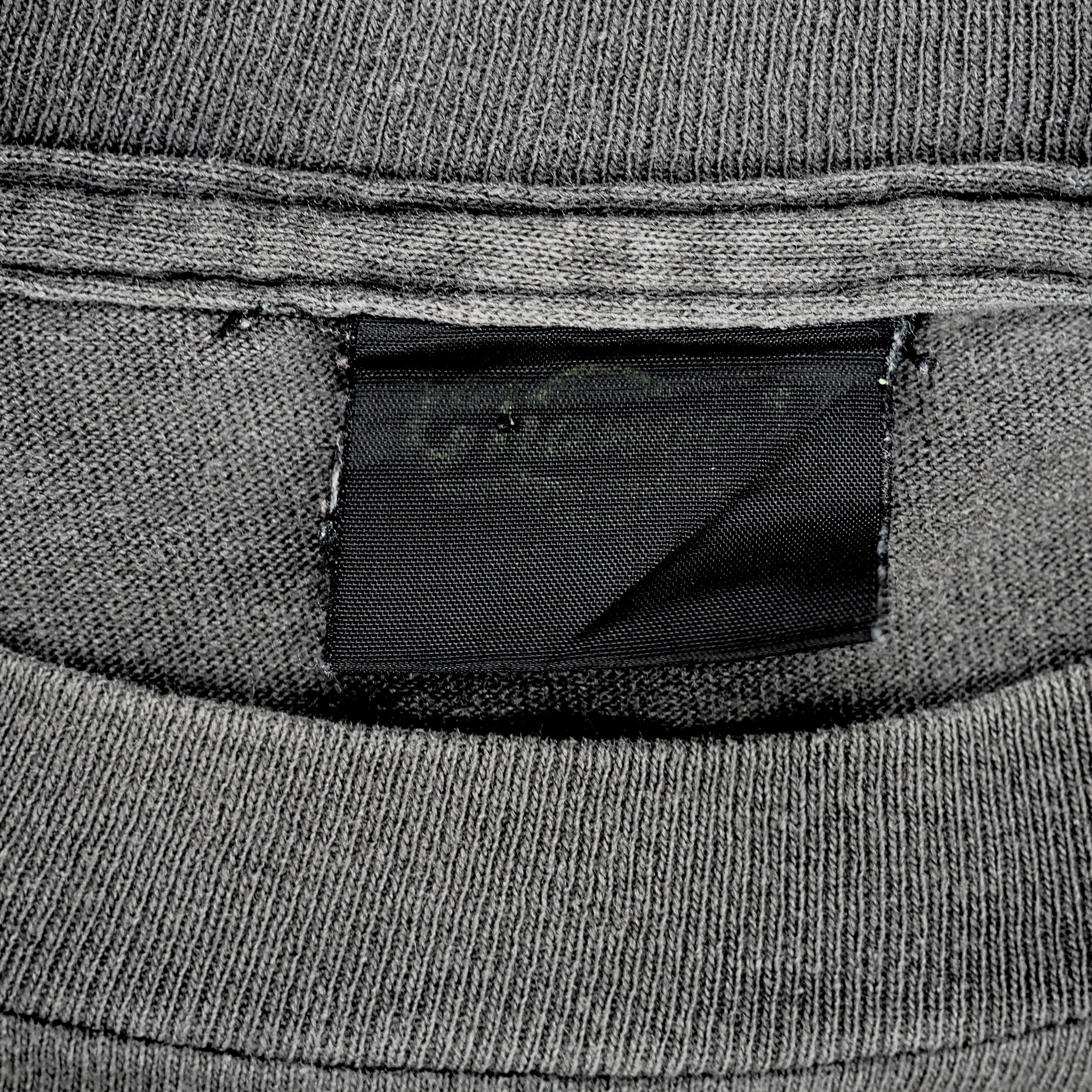 Close up of a faded black brand tag which reads 'Changes' on the inside collar of a grey t-shirt