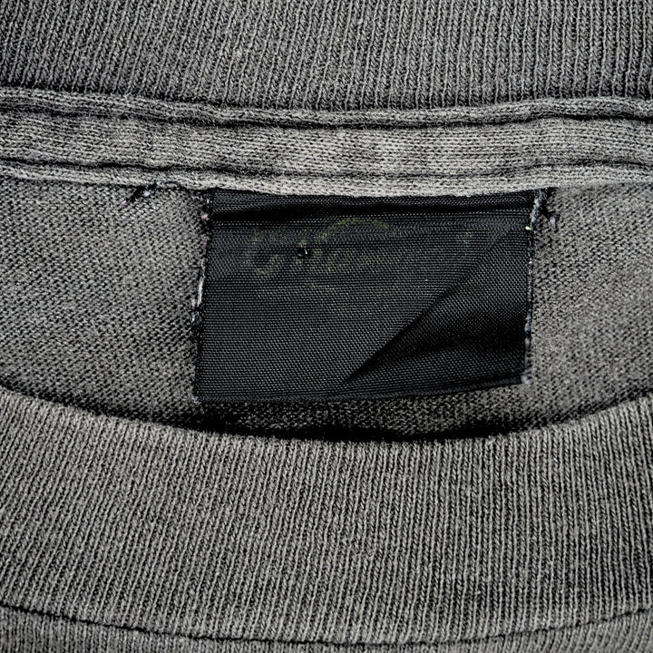 Close up of a faded black brand tag which reads 'Changes' on the inside collar of a grey t-shirt