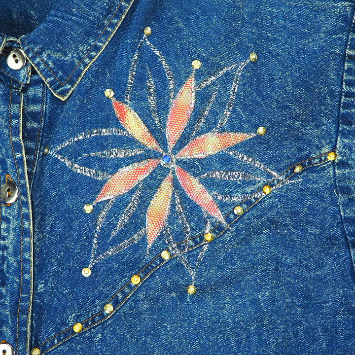 Close-up of an acid washed blue denim shirt with a colorful embroidered and beaded flower design