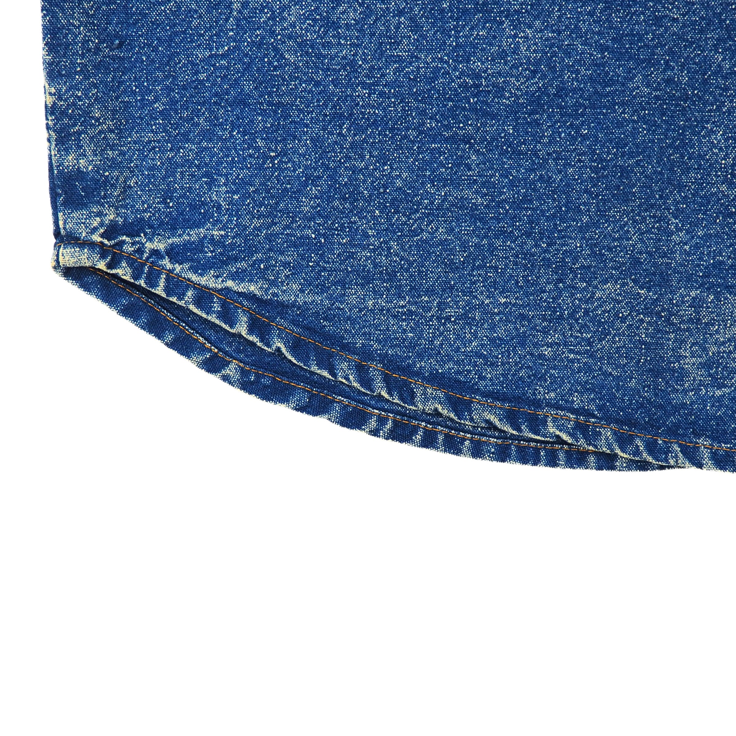 Close-up of blue acid wash denim shirt hem seam on a white background
