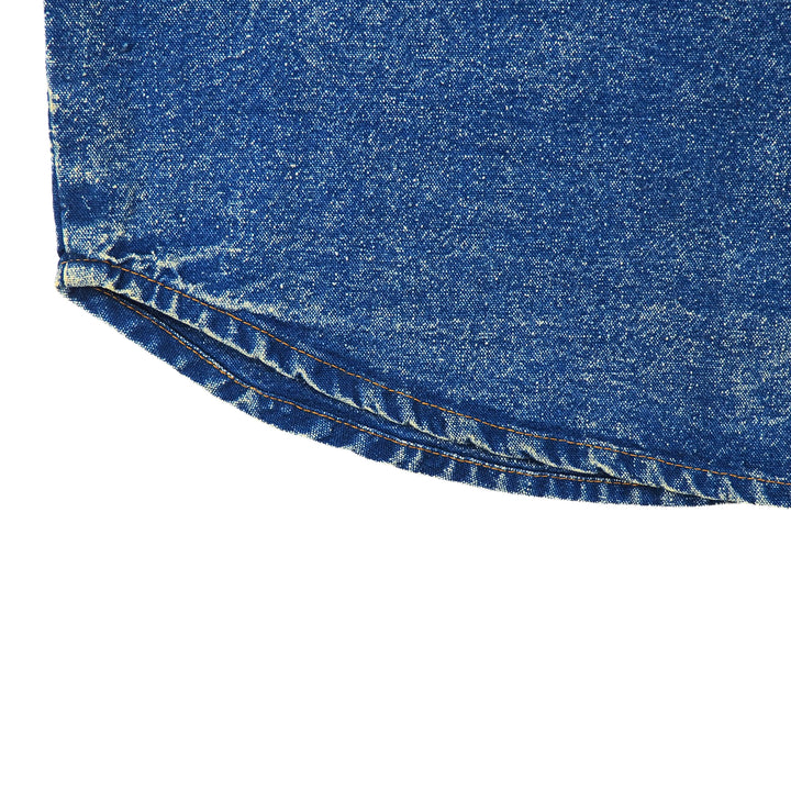 Close-up of blue acid wash denim shirt hem seam on a white background