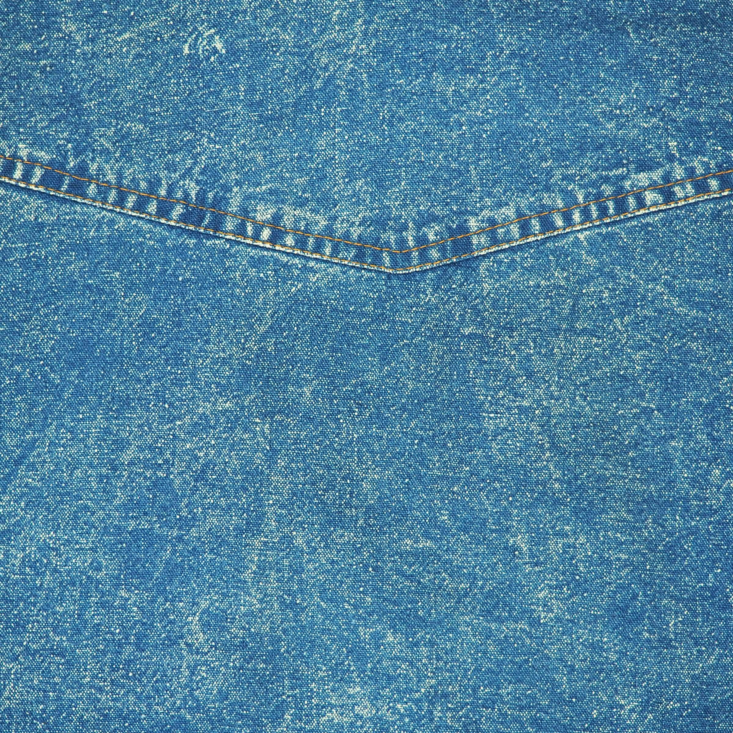 Close-up of blue denim fabric with orange stitching detail