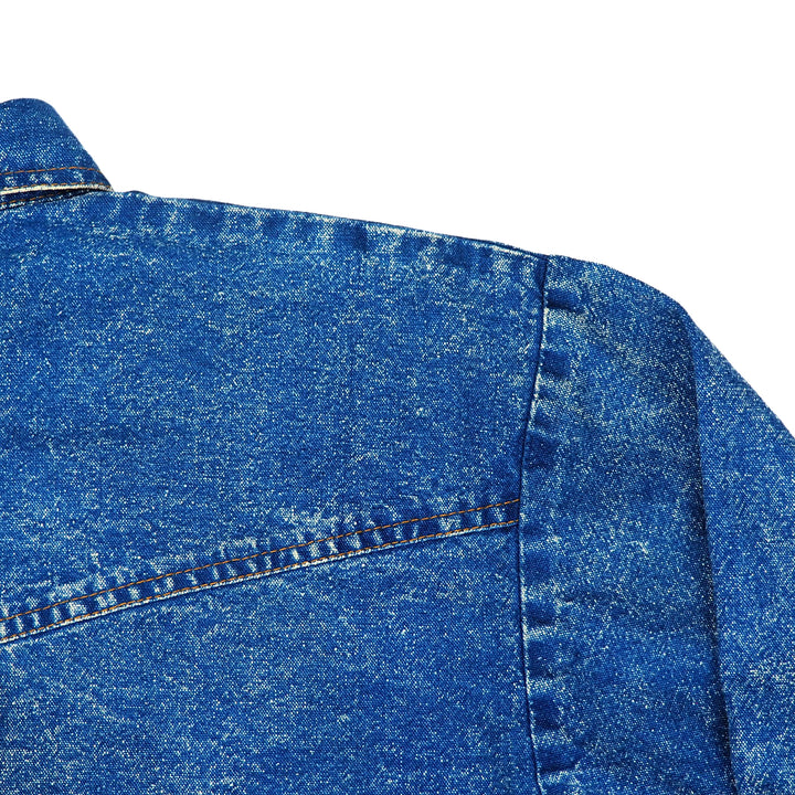 Close-up of blue denim shirt shoulder with stitching details on a white background