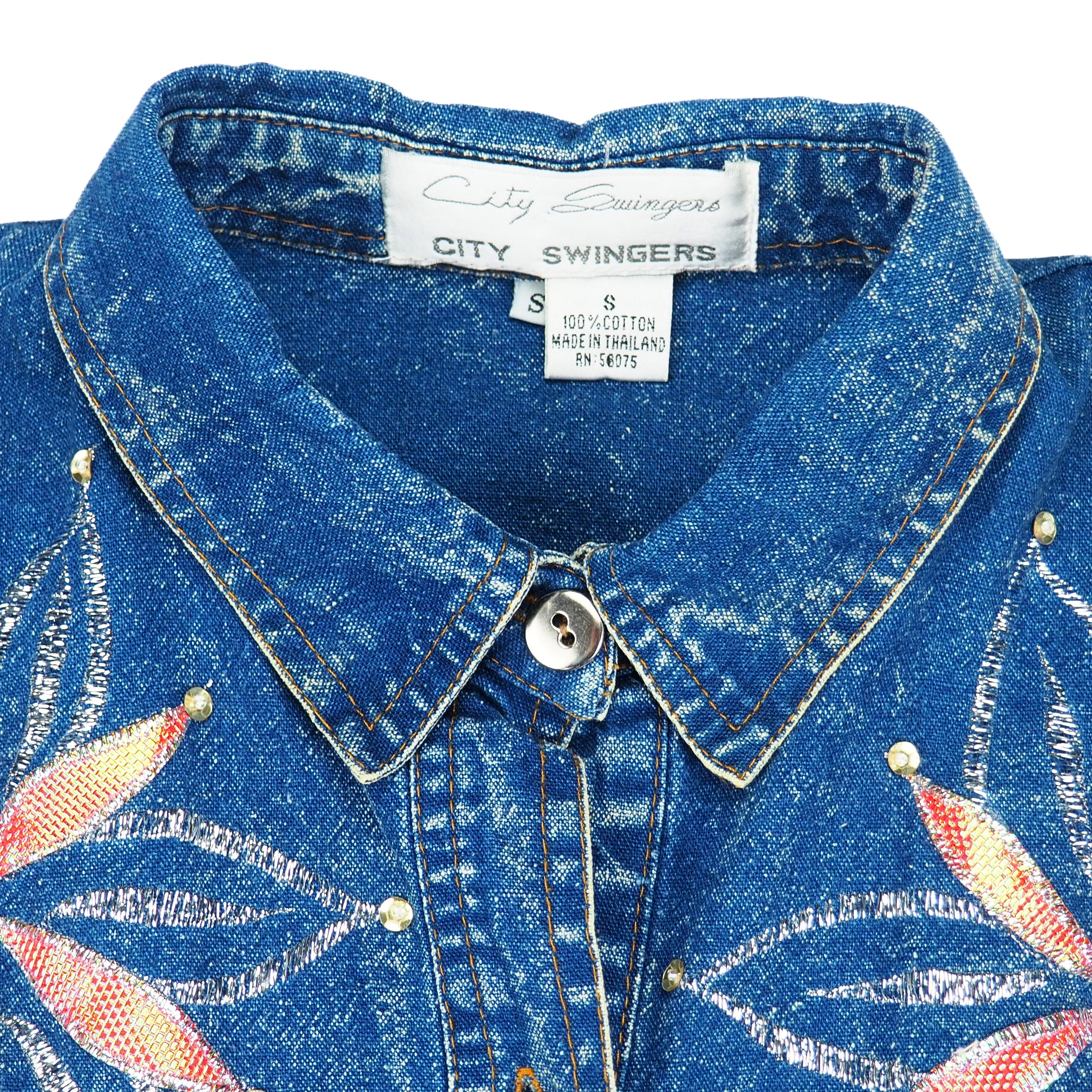 Close-up of a blue denim shirt with floral pattern on chest and 'City Swingers' label inside collar.
