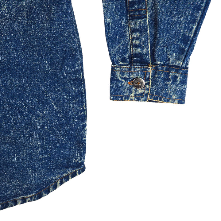 Close-up shirt tail and sleeve cuff detail of a blue acid wash denim shirt on a white background