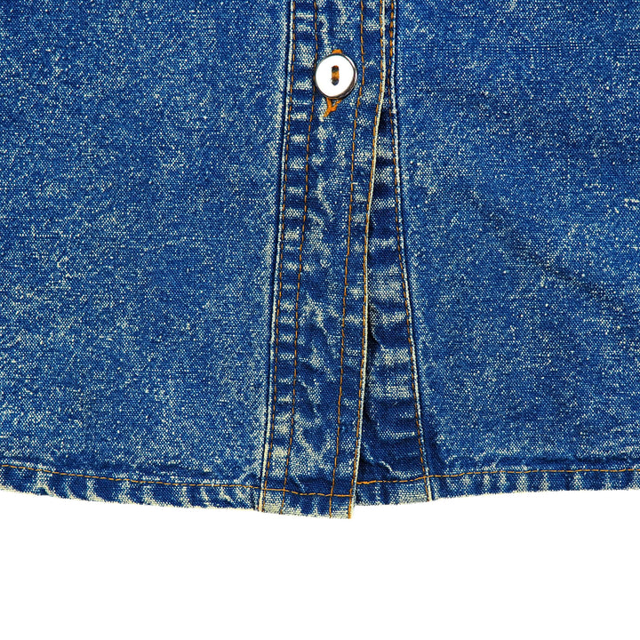 Close-up of blue denim fabric with a metallic silver button on a white background